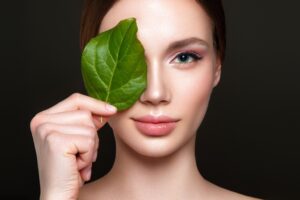 Image of woman holding a leaf over her right eye