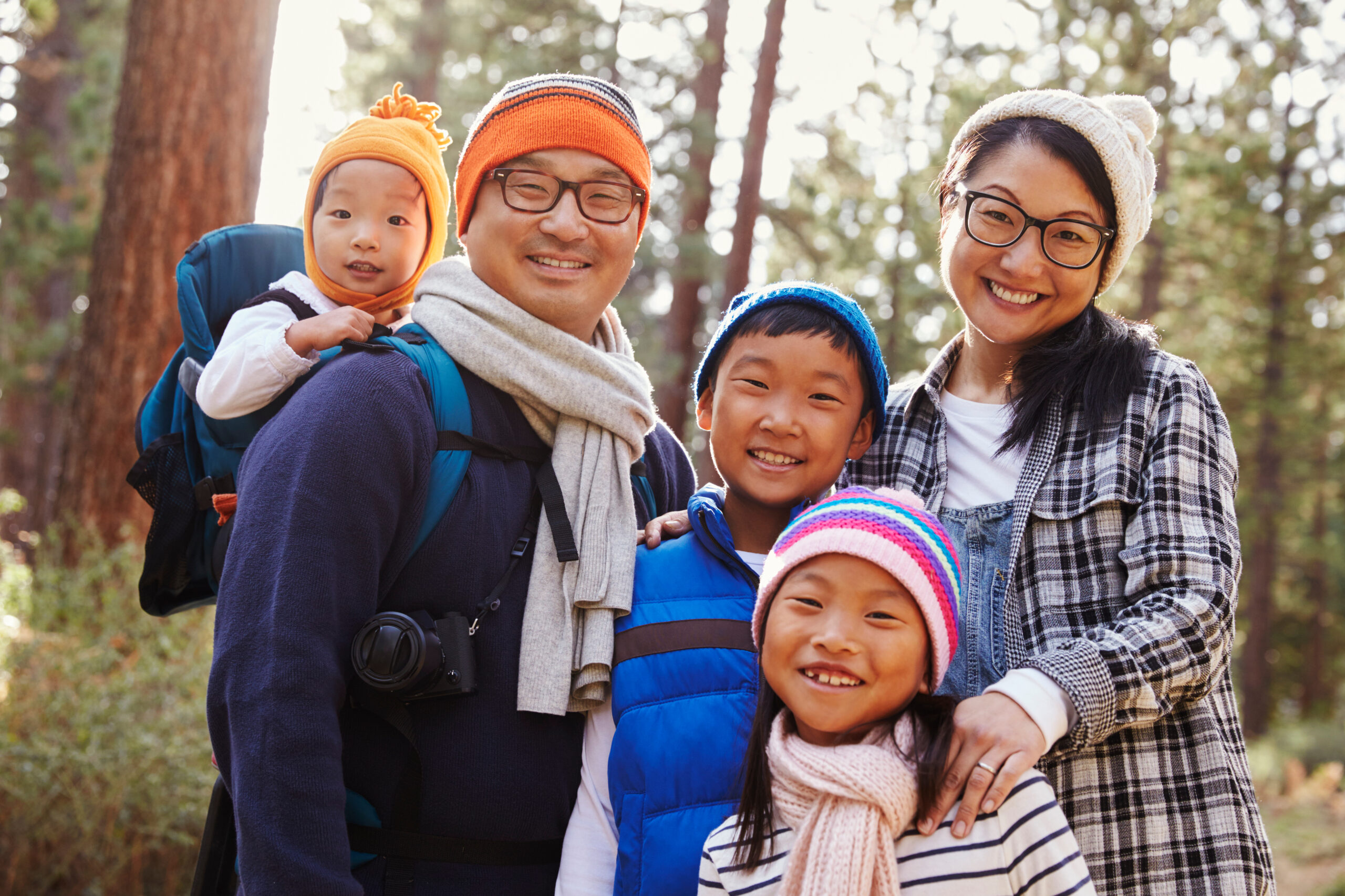 Portrait of an Asian family of five in a forest setting – B-Town Eyecare